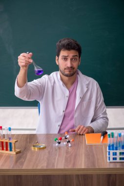 Young chemistry teacher sitting in the classroom