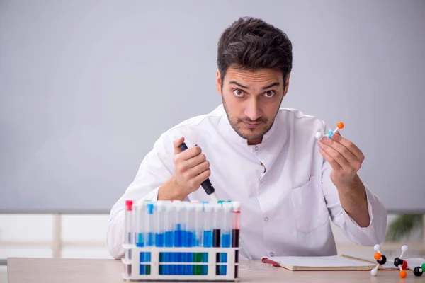 Young chemist teacher sitting in the classroom