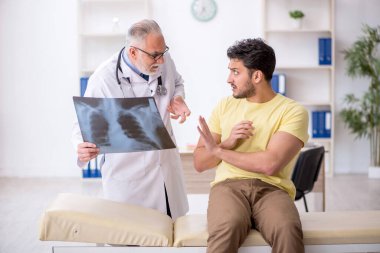 Genç hasta yaşlı doktoru ziyaret ediyor.