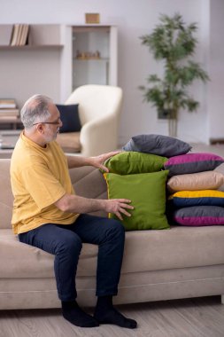 Evde bir sürü yastığı olan yaşlı bir adam.