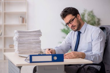 Young employee and too much work at workplace