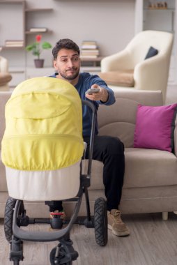 Evde yeni doğan çocuğa bakan adam.