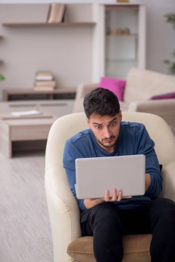 Genç erkek öğrenci salgın sırasında evden çalışıyor.