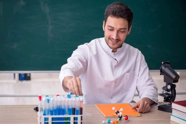 年轻的化学家老师坐在教室里 — 图库照片