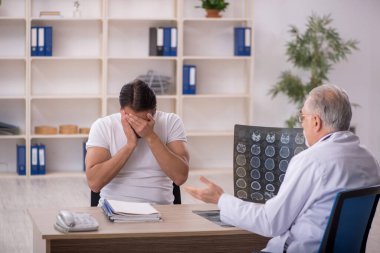 Genç hasta yaşlı erkek doktor radyolojisti ziyaret ediyor.