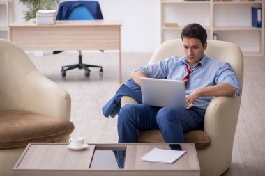 Genç işadamı işyerinde oturuyor.