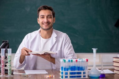 Young chemist in front of green board