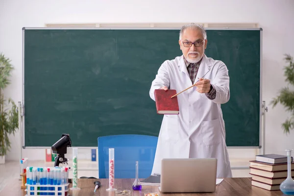 Old teacher chemist sitting in the classroom