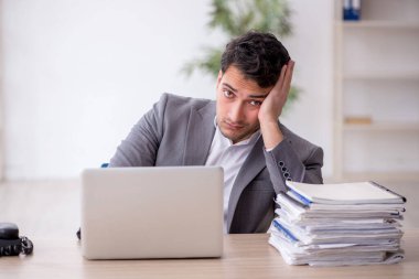Young employee and too much work at workplace