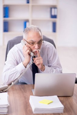 Old businessman employee unhappy with excessive work at workplace