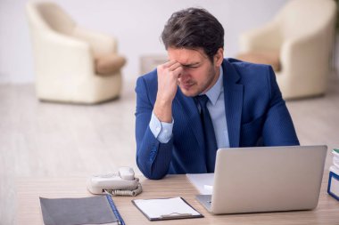 Genç işadamı işyerinde oturuyor.