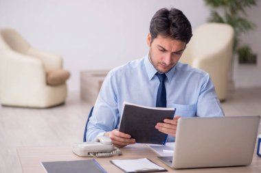 Genç işadamı işyerinde oturuyor.