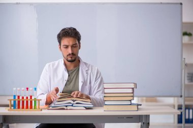 Genç kimyacı öğretmen beyaz tahtanın önünde.