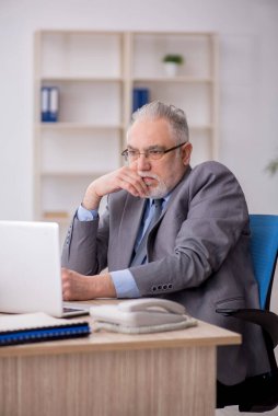 Old employee sitting at workplace