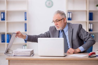 Old employee sitting at workplace