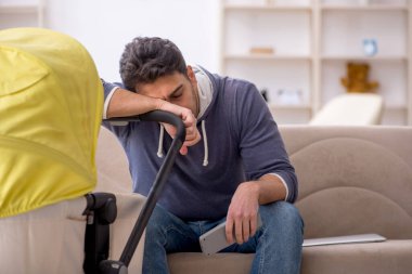 Genç erkek müteahhit evde yeni doğan bebeğe bakıyor.