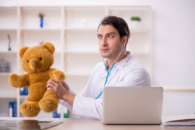 Genç doktor oyuncak ayı tutuyor.