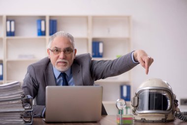 Old employee wearing spacesuit in the office