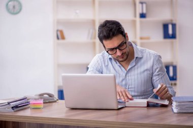 Young businessman employee reading book at workplace