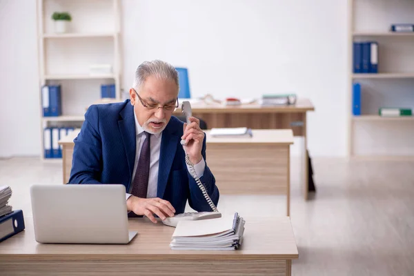 stock image Old employee sitting at workplace