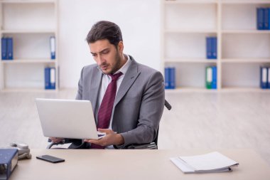 Young male employee in wheel-chair working at workplace