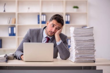 Young employee and too much work at workplace
