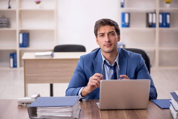 Young male employee and too much work at workplace