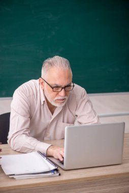 Old teacher sitting in the classroom