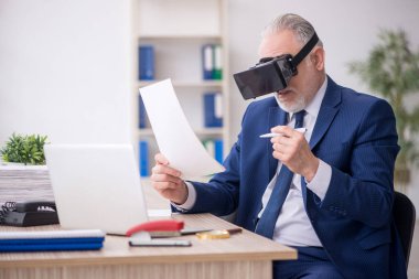 Old businessman employee wearing virtual glasses in the office