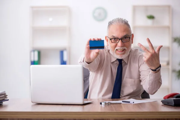 Old employee holding credit card at workplace