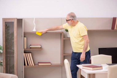 Yaşlı adam evi temizliyor.