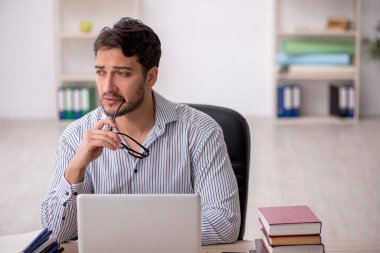 Genç erkek öğrenci işyerinde oturuyor.