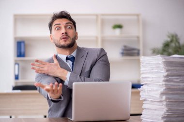 Young employee and too much work at workplace