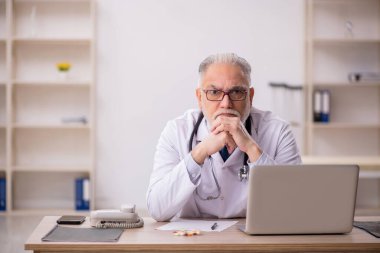 Klinikte çalışan yaşlı bir doktor.