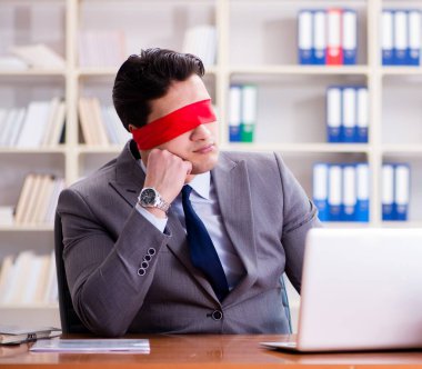 Ofiste masasında oturan gözü bağlı iş adamı.