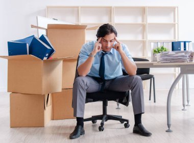 The young man employee with boxes in the office