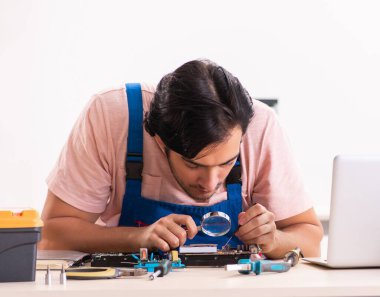 Genç erkek müteahhit bilgisayarı tamir ediyor.