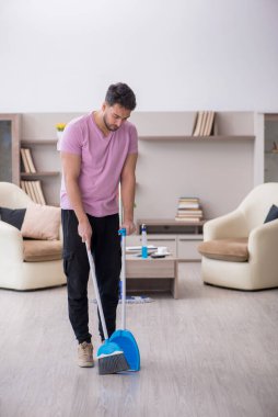 Genç müteahhit evi temizliyor.