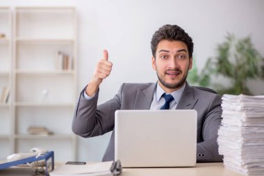 Young employee and too much work at workplace