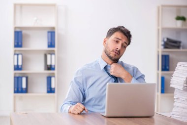 Young employee and too much work at workplace