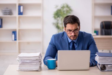 Genç işadamı ve işyerinde çok fazla iş var.