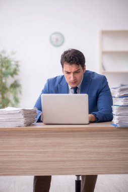 Genç işadamı ve işyerinde çok fazla iş var.