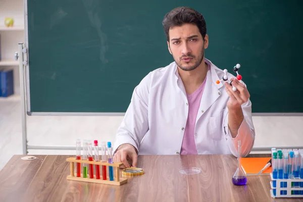 教室に座っている若い化学の先生 — ストック写真