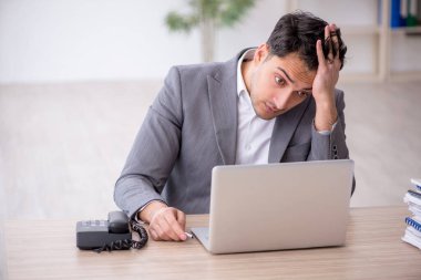 Young employee and too much work at workplace