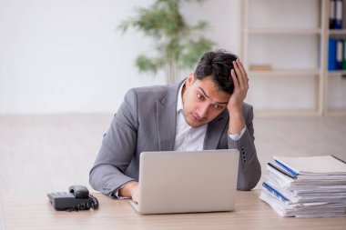 Young employee and too much work at workplace