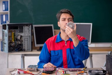 Sınıfta bilgisayar tamir eden genç bir tamirci.