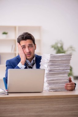 Young employee and too much work at workplace
