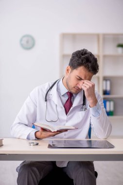 Hastanede kitap okuyan genç bir doktor.