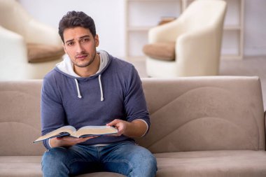 Evde kitap okuyan genç bir öğrenci.