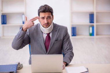 Young employee after car accident sitting at workplace